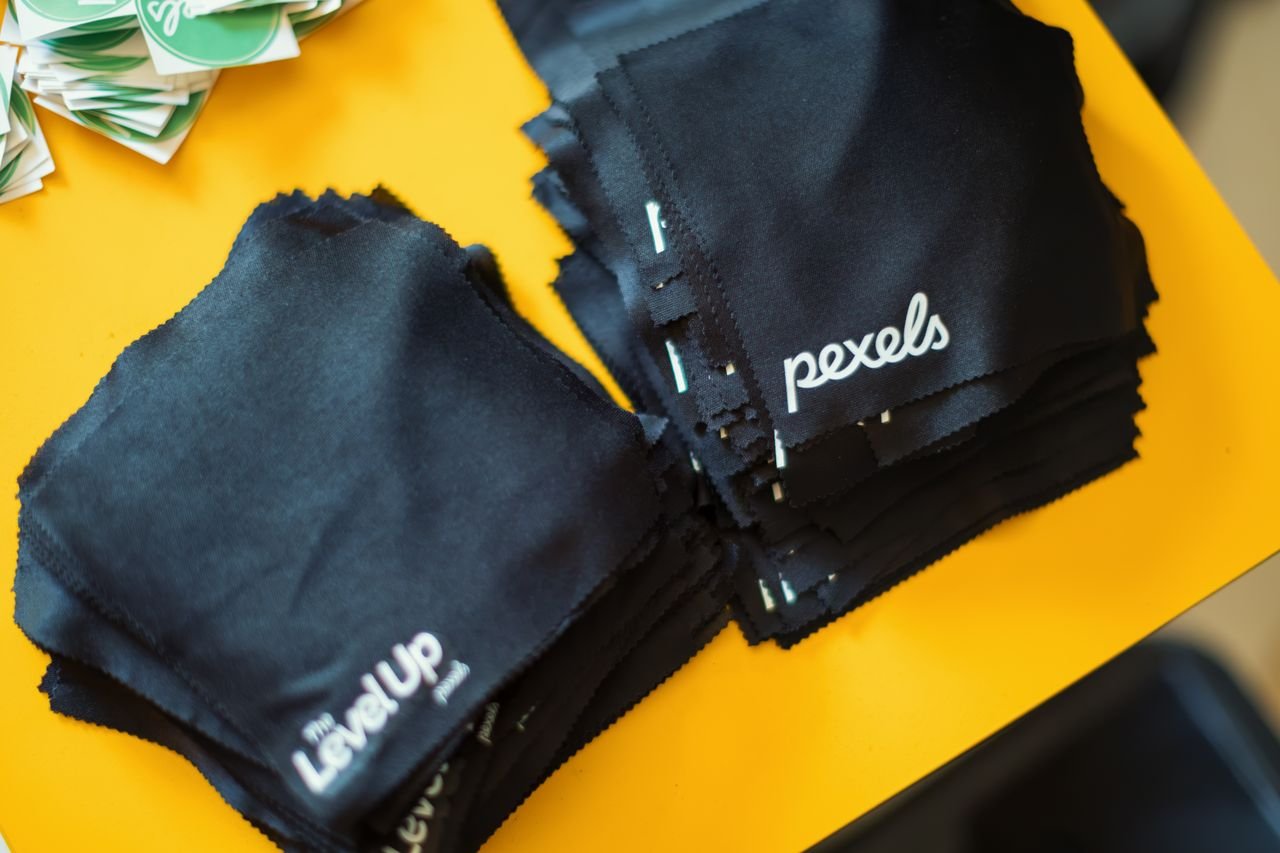 services-02 Stacked black microfiber cleaning cloths with branding on bright yellow background.