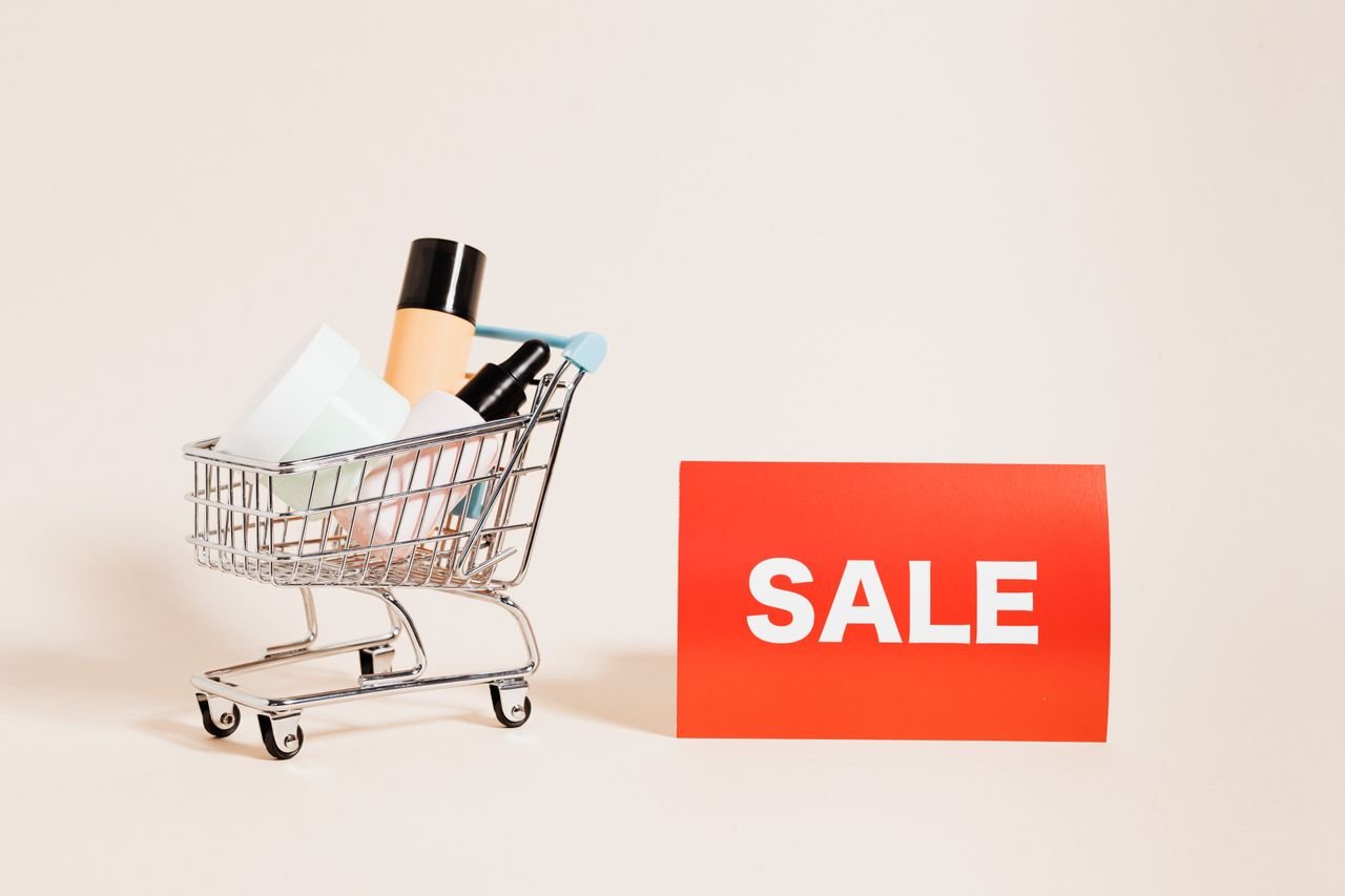 The Art of Drawing Readers In: Your attractive post title goes here A miniature shopping cart filled with products beside a bright sale sign, ideal for retail and marketing concepts.