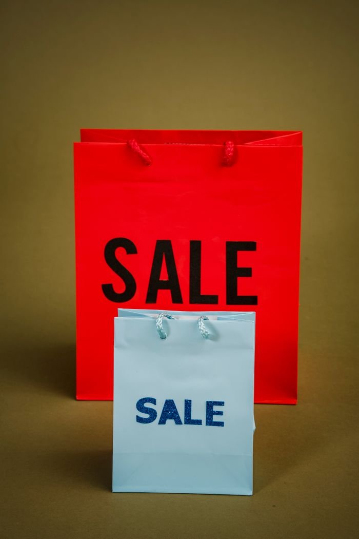 Red and white shopping bags labeled 'SALE' ready for promotional use.