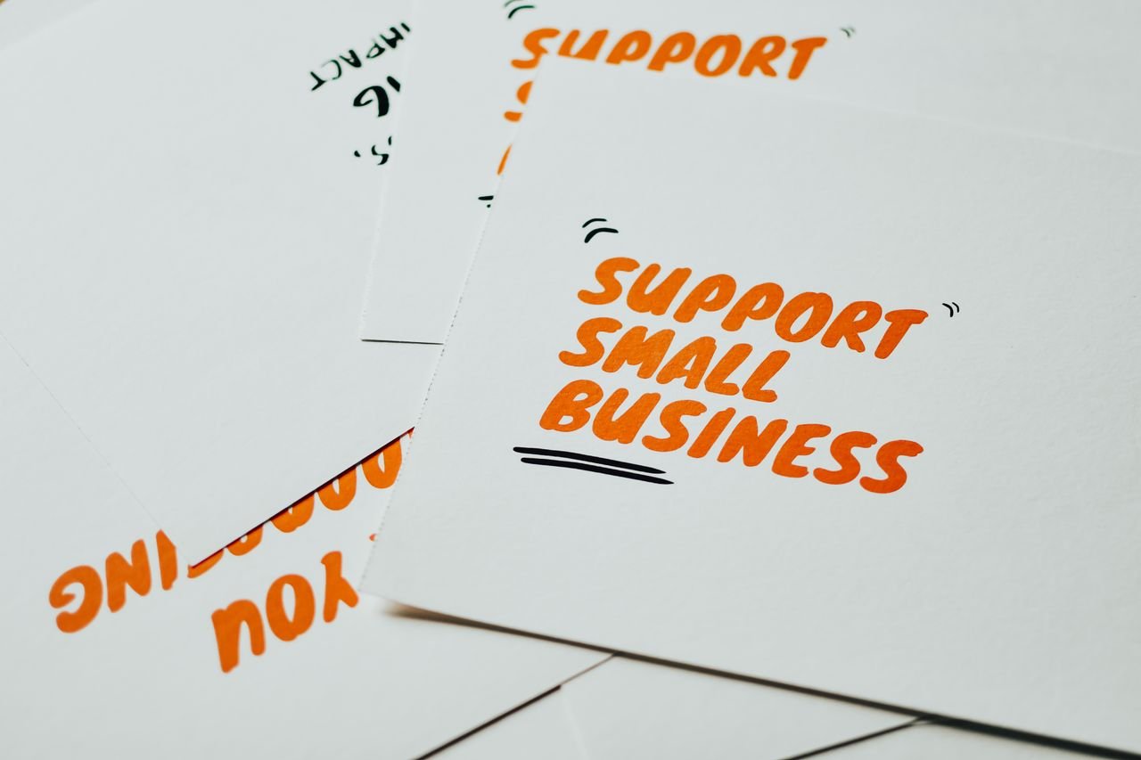 Close-up of motivational cards promoting support for small business on white background.